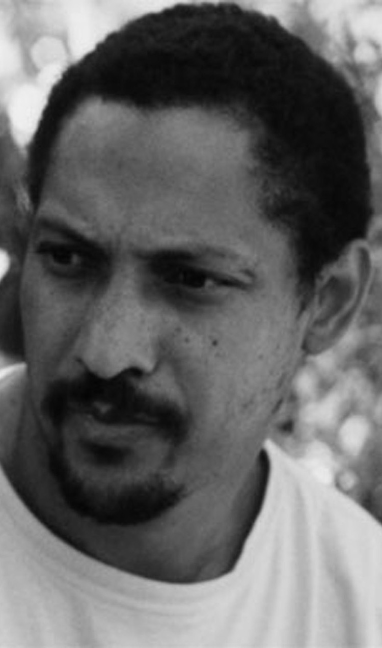 A black and white image of a black man in a white t-shirt looking to his right